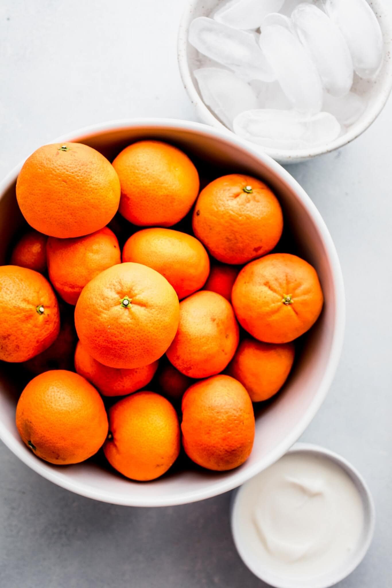Bowl of clementines next to small bowl of yogurt.