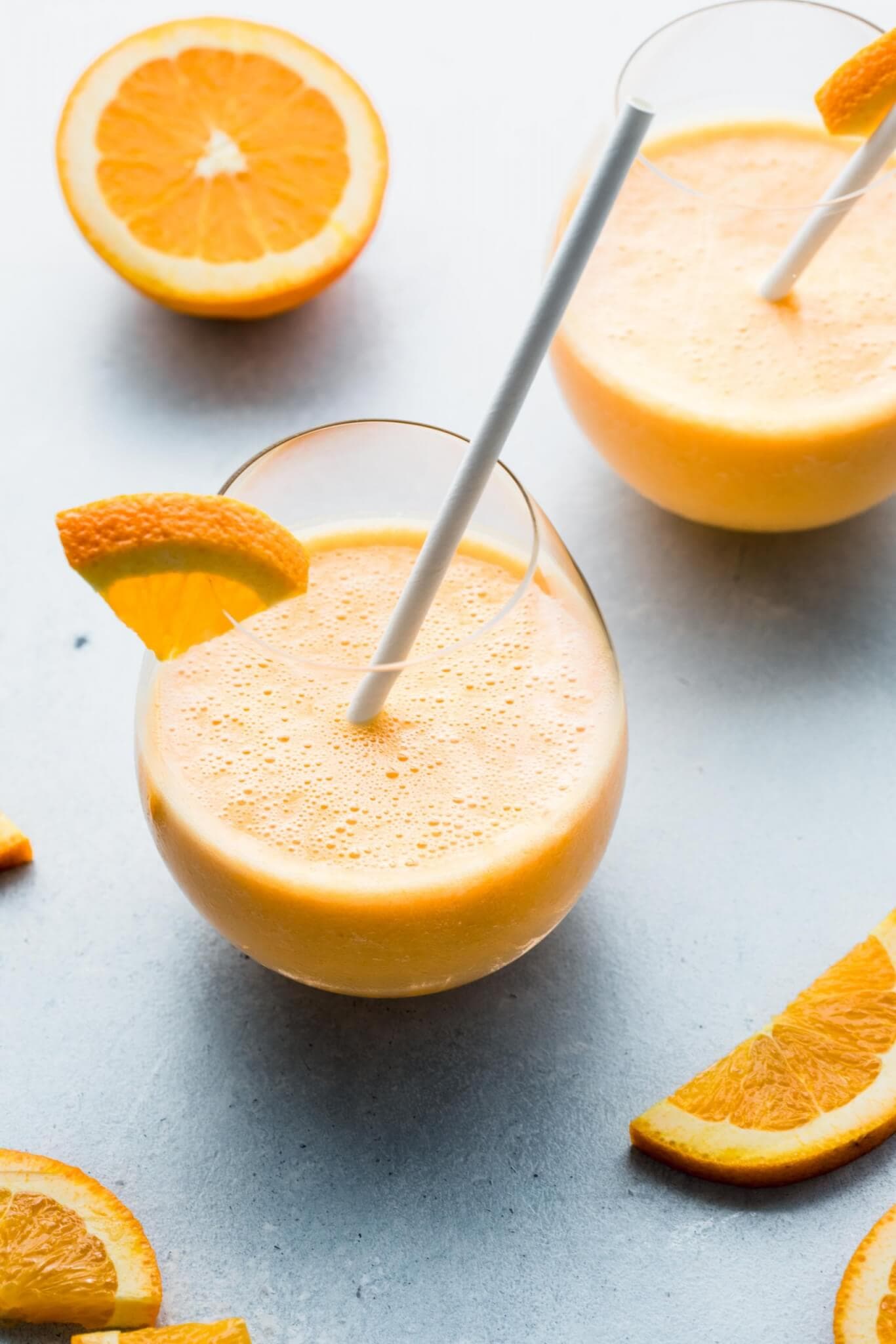 Side view of two clementine smoothies in glass cups. 