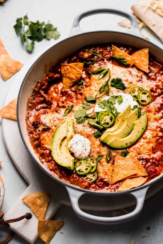 Side view of enchilada dip surrounded by chips. 