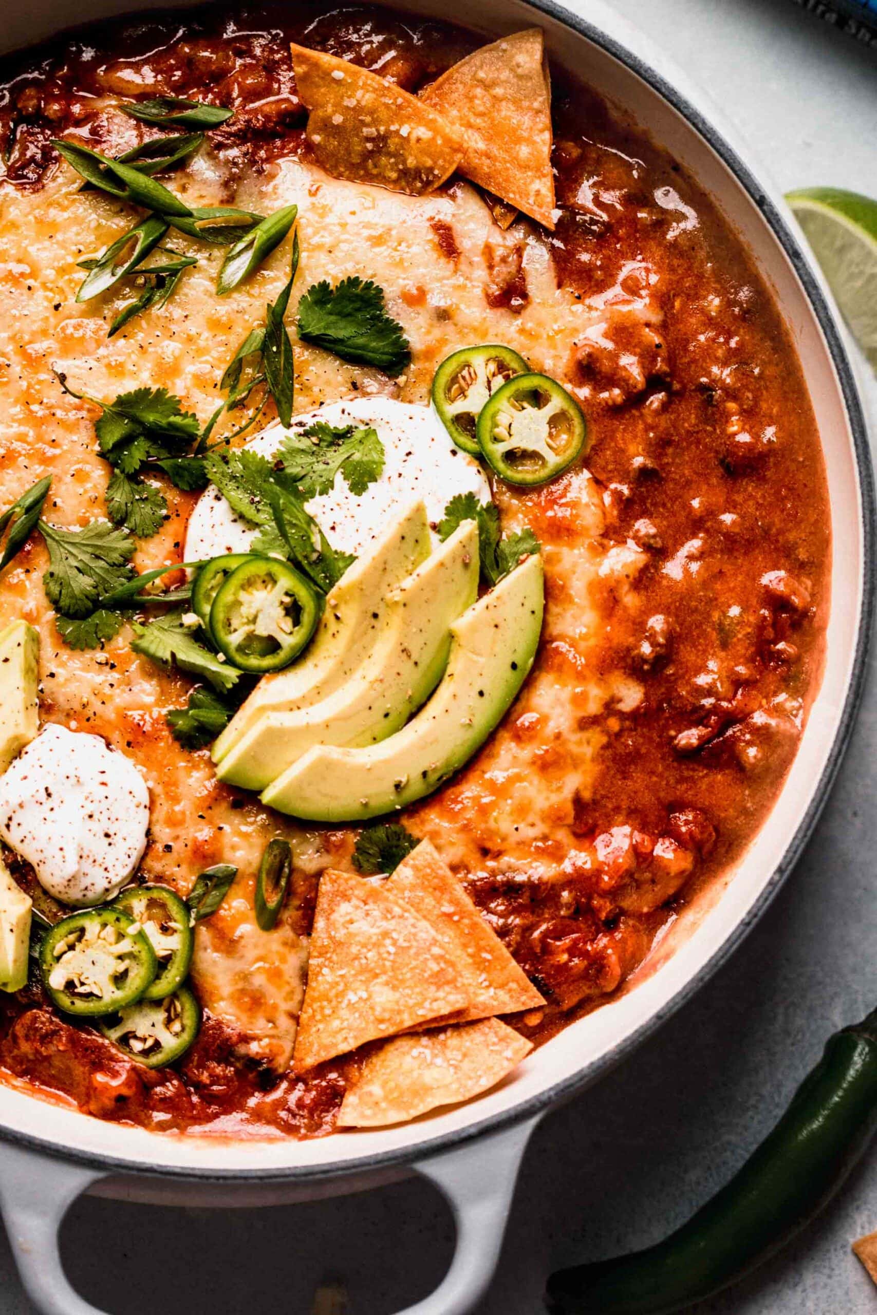 Overhead close up of enchilada dip topped with jalapenos and avocado slices.