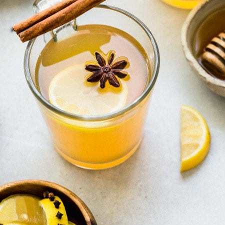 HOT TODDY IN MUG WITH CINNAMON STICK AND STAR ANISE.