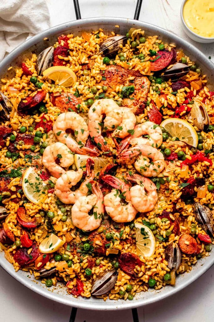 Overhead shot of paella in pan topped with shrimp and clams.
