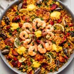 Paella in pan topped with dollops of aioli.