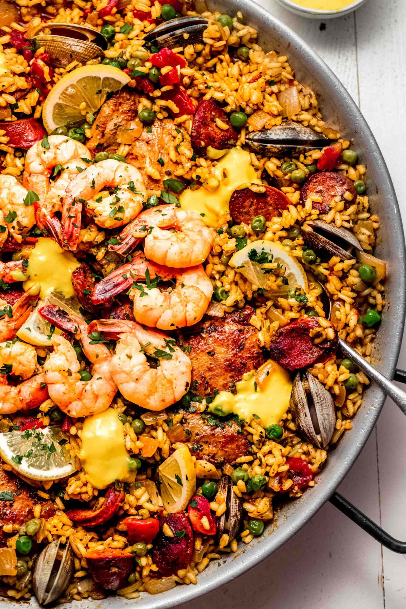 Seafood paella in pan topped with saffron aioli.