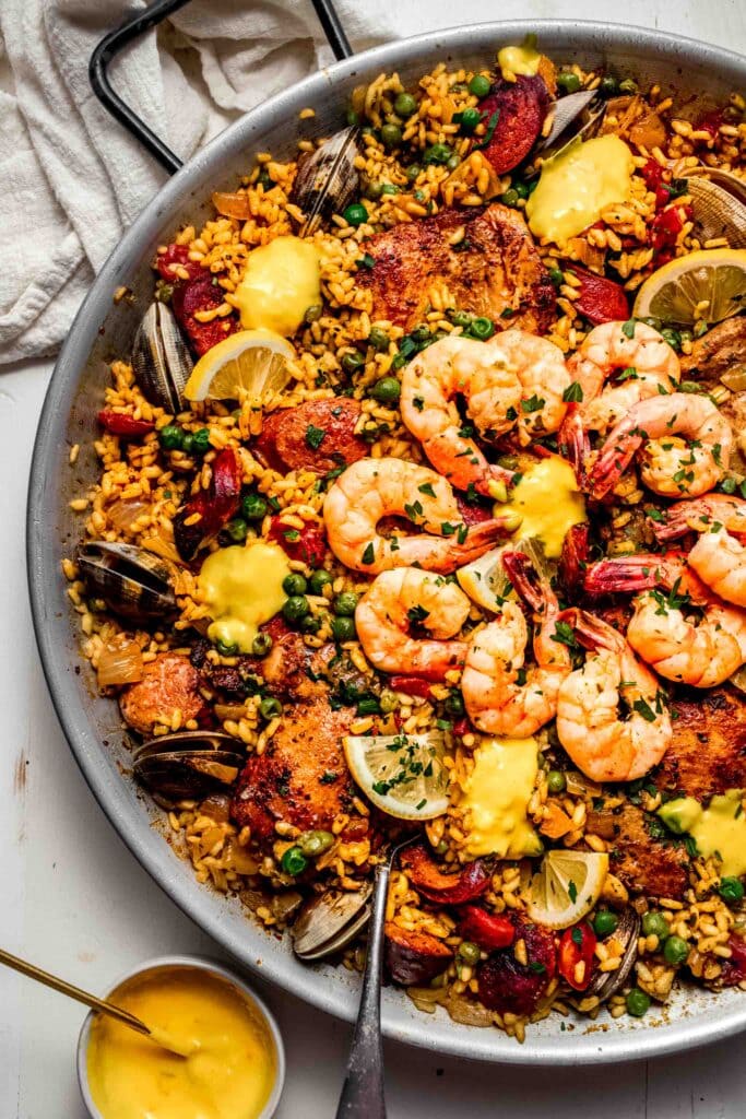 Seafood paella in pan topped with saffron aioli.