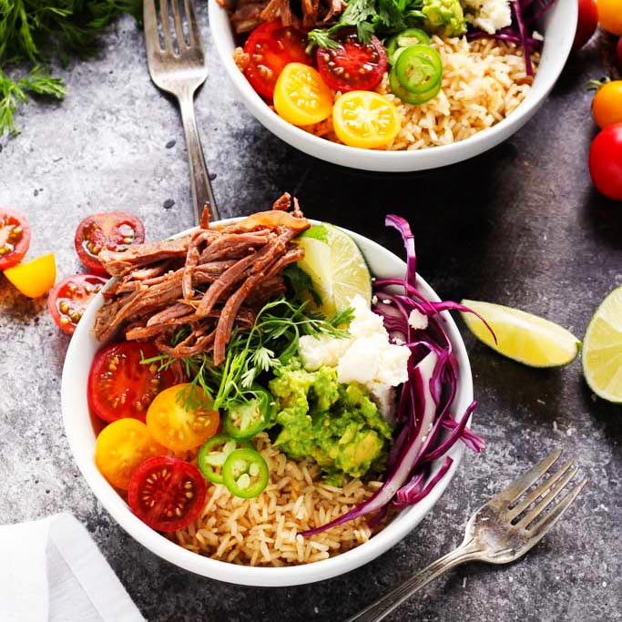These Slow Cooker Steak Carnitas Bowls are super simple to make with the help of your crockpot. Finish them off with a quick guacamole and a combination of your favorite toppings for a healthy weeknight dinner | platingsandpairings.com