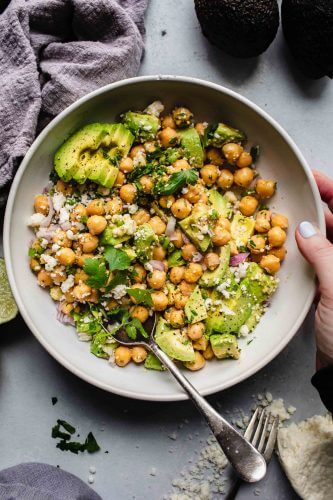 Hand holding bowl of chickpea salad.