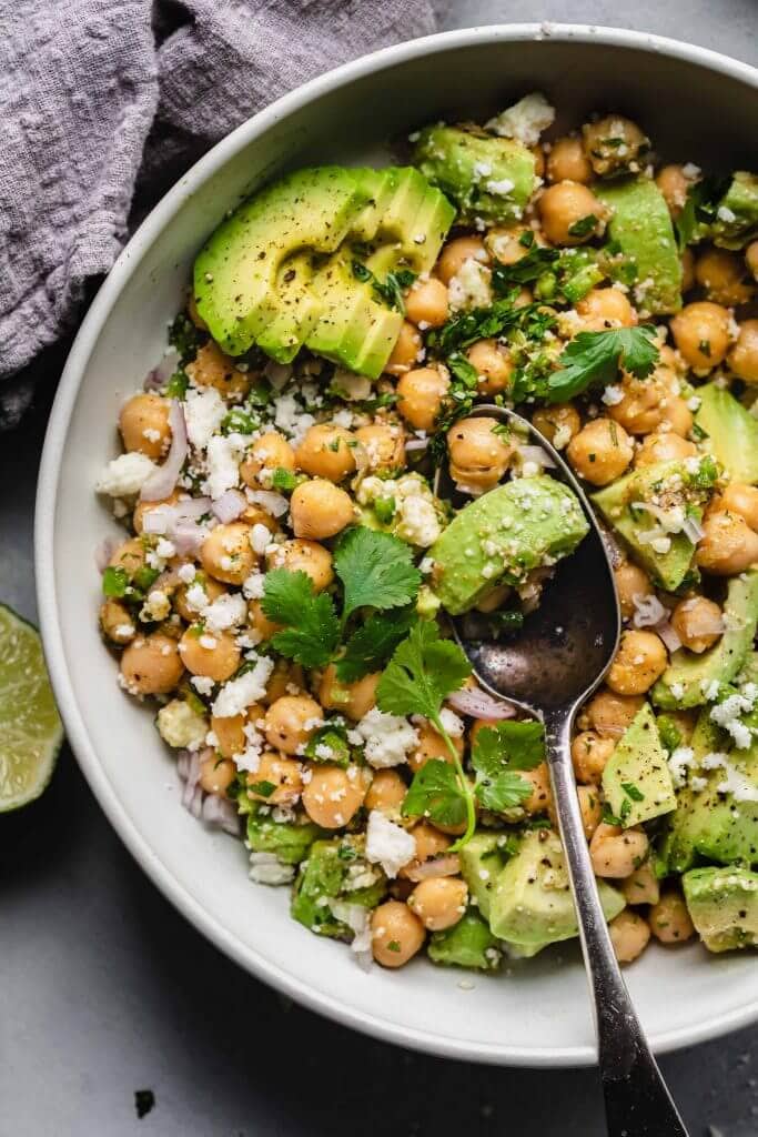 Overhead close up of bowl of avocado salad with chickpeas. 