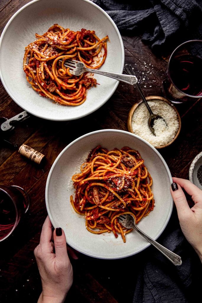 Hands holding plate of pasta.