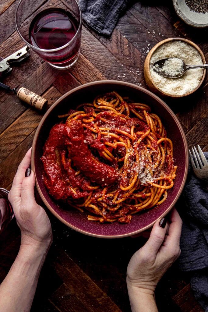 Hands holding bowl of sunday gravy. 