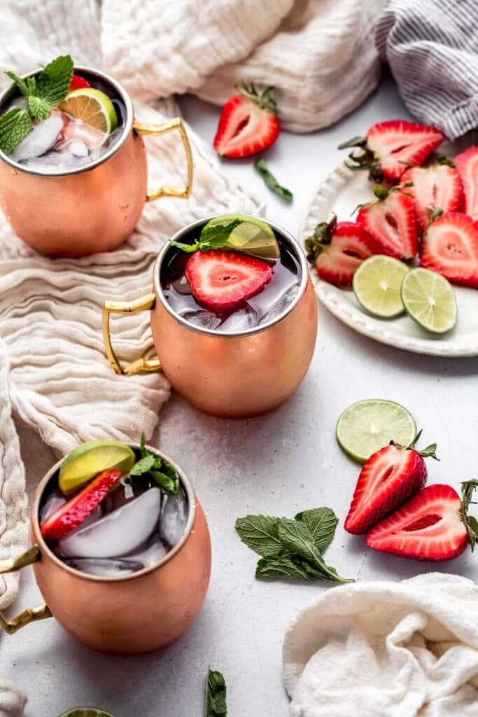 Three strawberry moscow mules on counter.