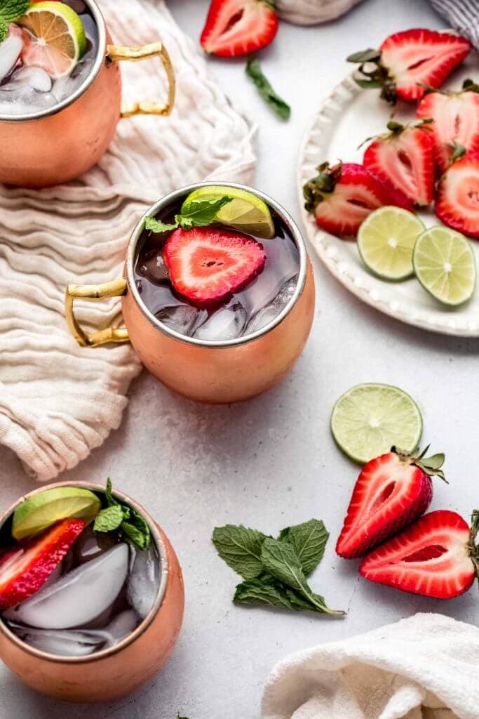 Three strawberry moscow mules on counter.