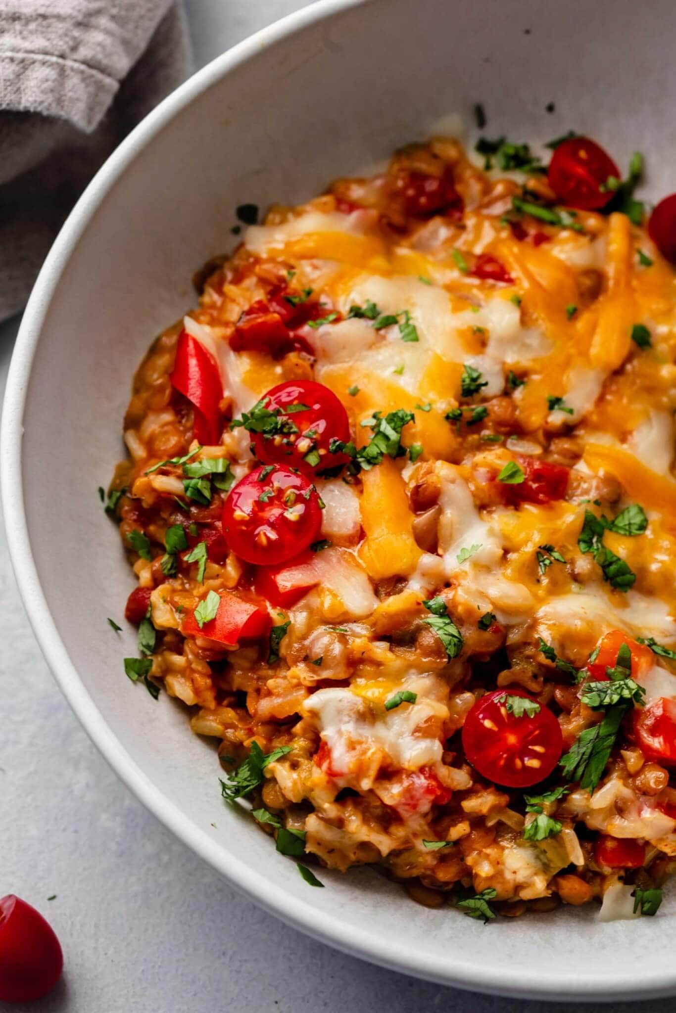 Close up of lentils topped with cheese in bowl.