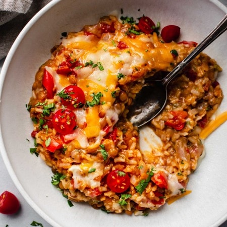 Bowl of cheesy lentils with spoon.