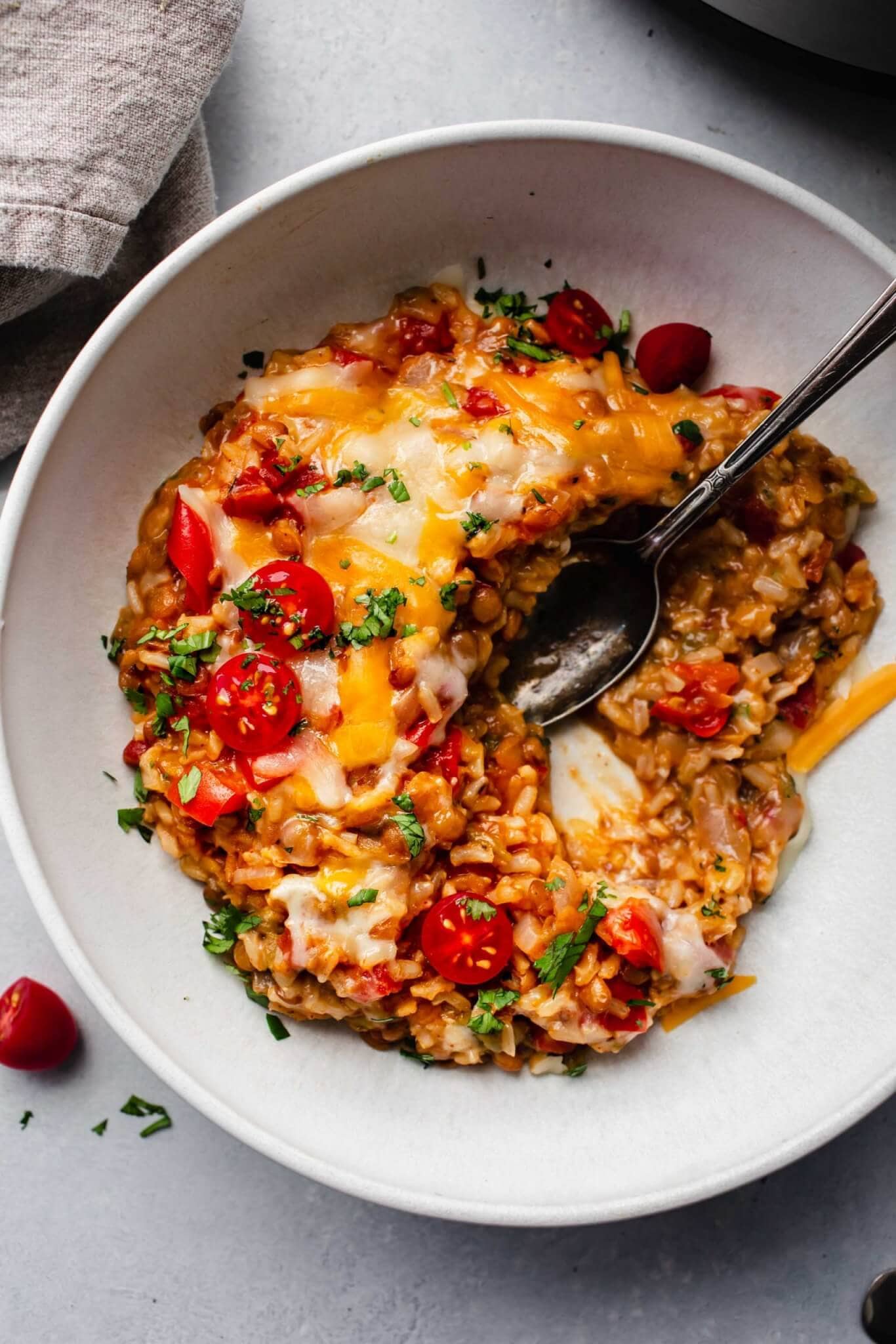 Bowl of cheesy lentils with spoon.