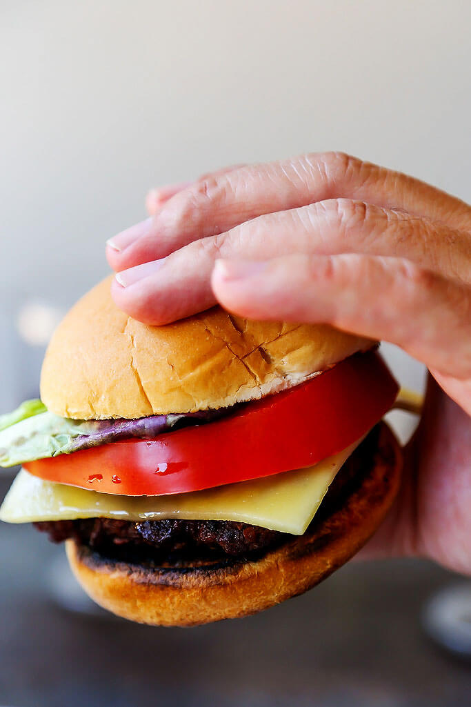 These Red Wine Burgers are decadent treat for your summer BBQ. Seasoned with a red wine-shallot reduction, topped with melted cheese and served simply with a thick slice of tomato and lettuce. | platingsandpairings.com