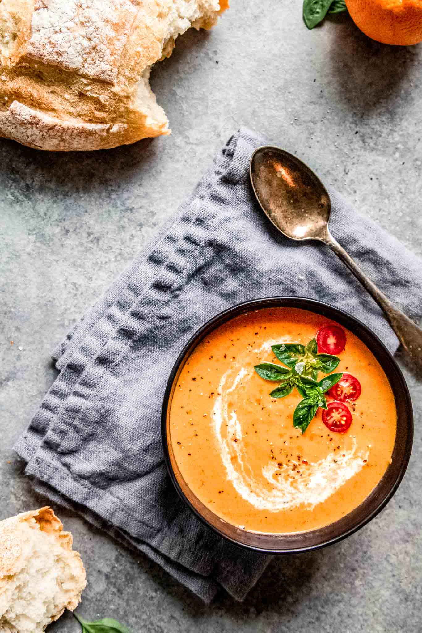 Bowl of tomato bisque next to bread. 