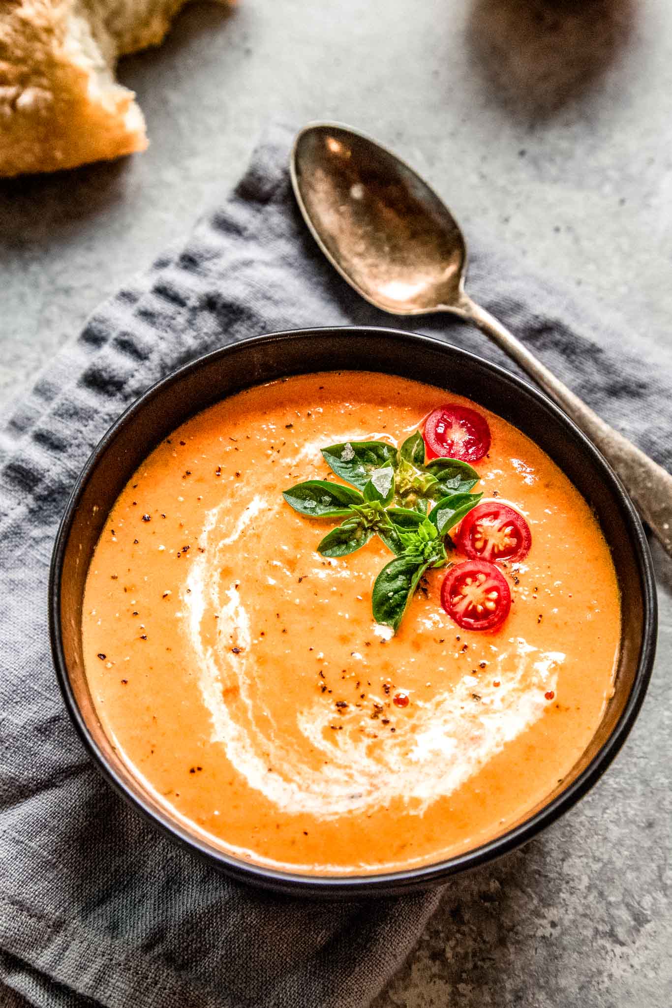 Bowl of tomato bisque next to bread. 