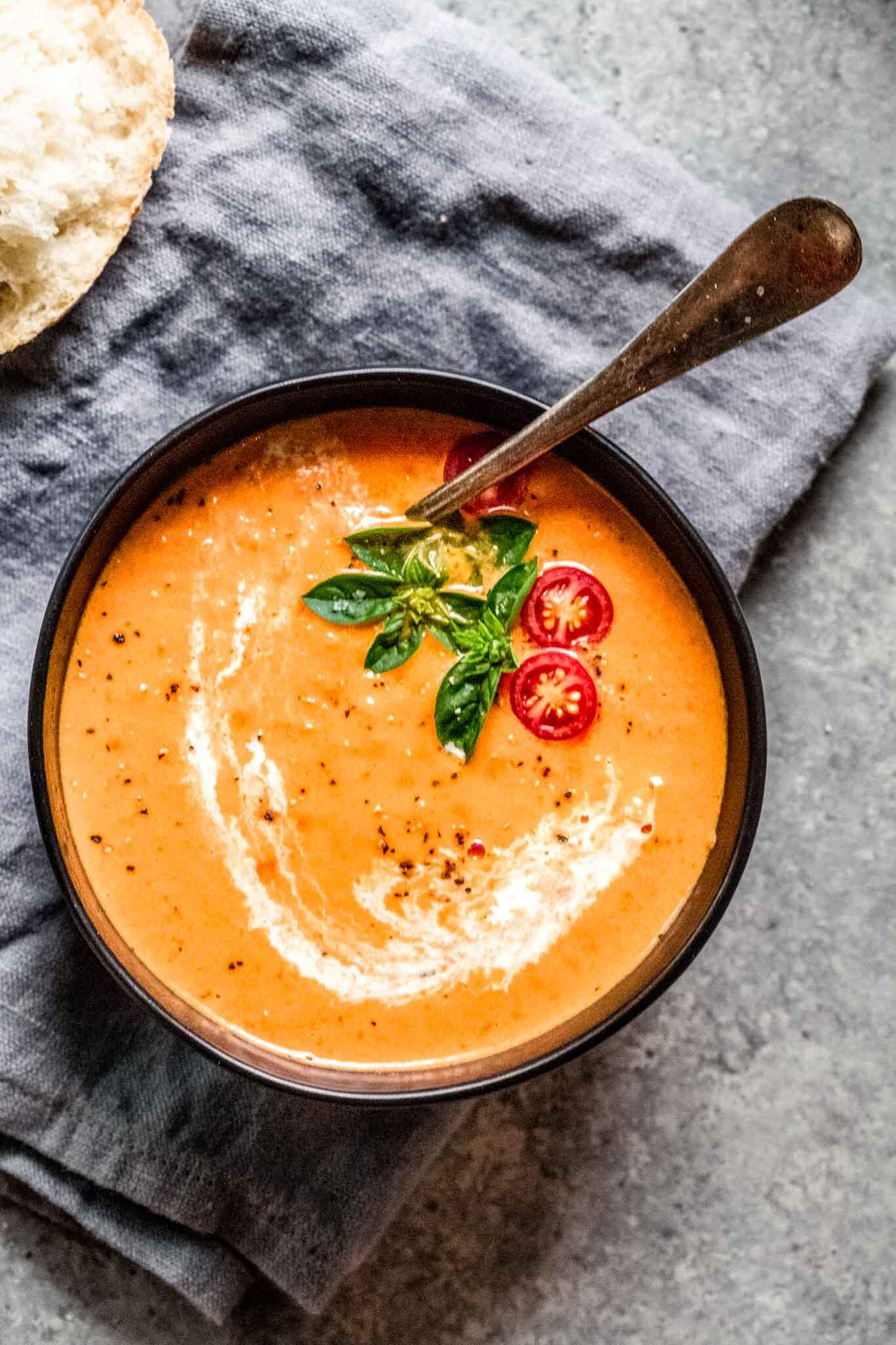 Bowl of tomato bisque next to bread.