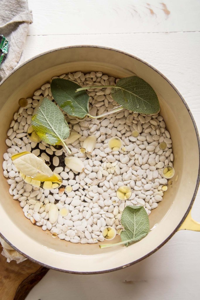 Italian white beans in pot before cooking with sage, garlic, bay leaf