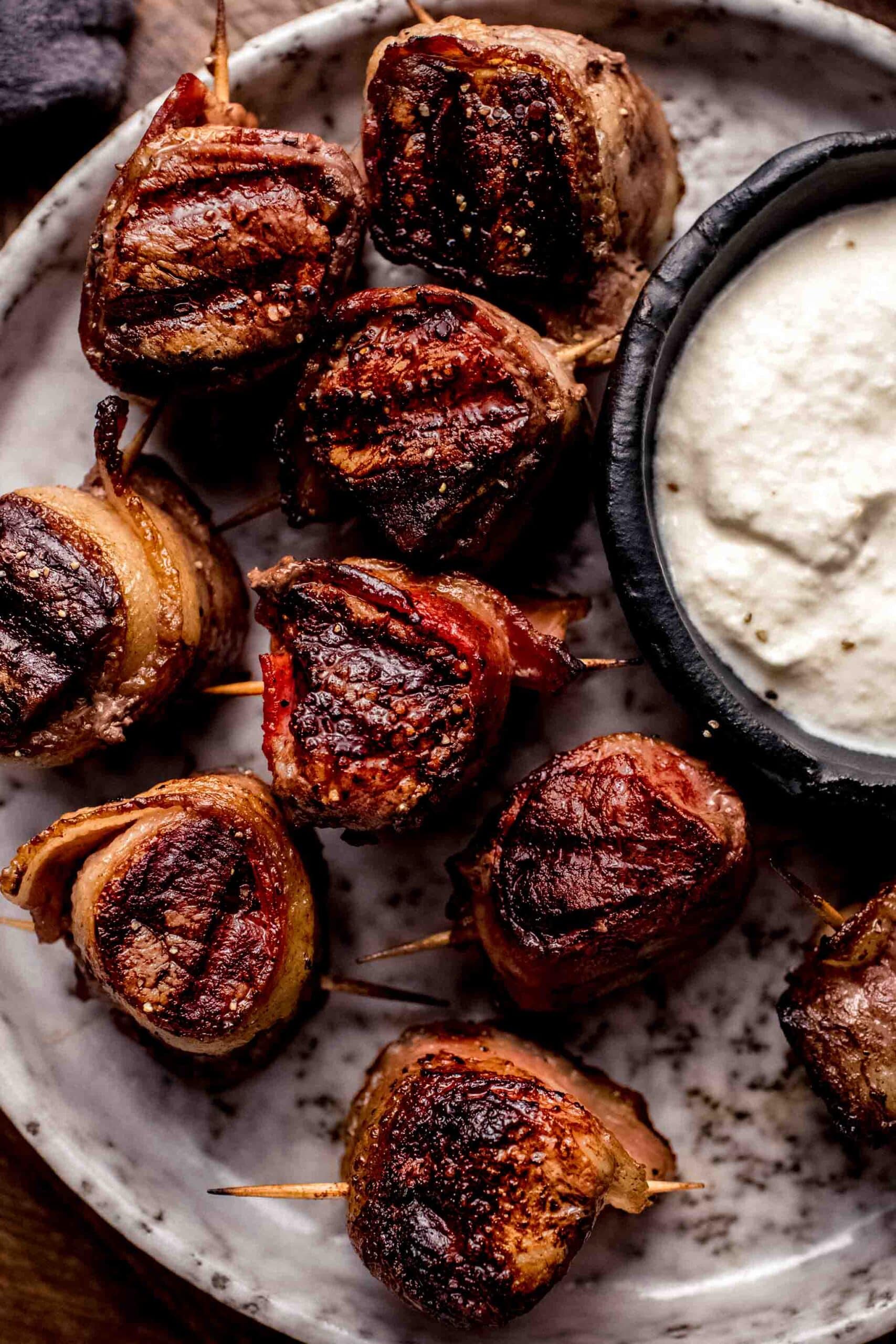 Filet mignon appetizers on plate with bowl of creamy horseradish sauce.