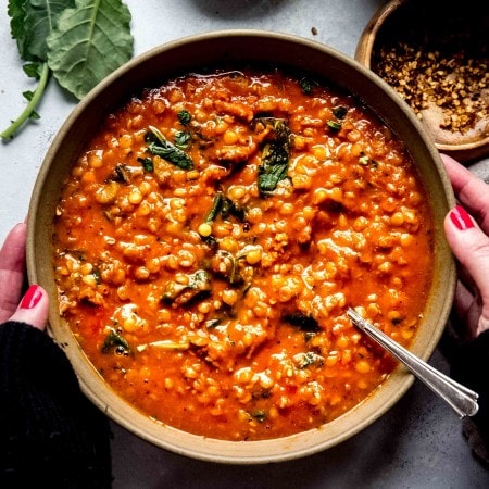 Overhead close up of hands holding bowl of lentil soup.