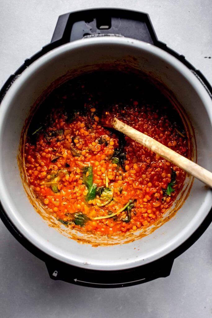 Lentil soup in the instant pot with wooden spoon. 