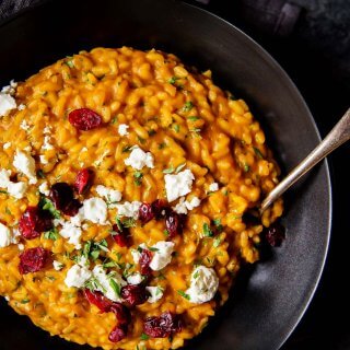 Overhead shot of pumpkin risotto in bowl with goat cheese & cranberries