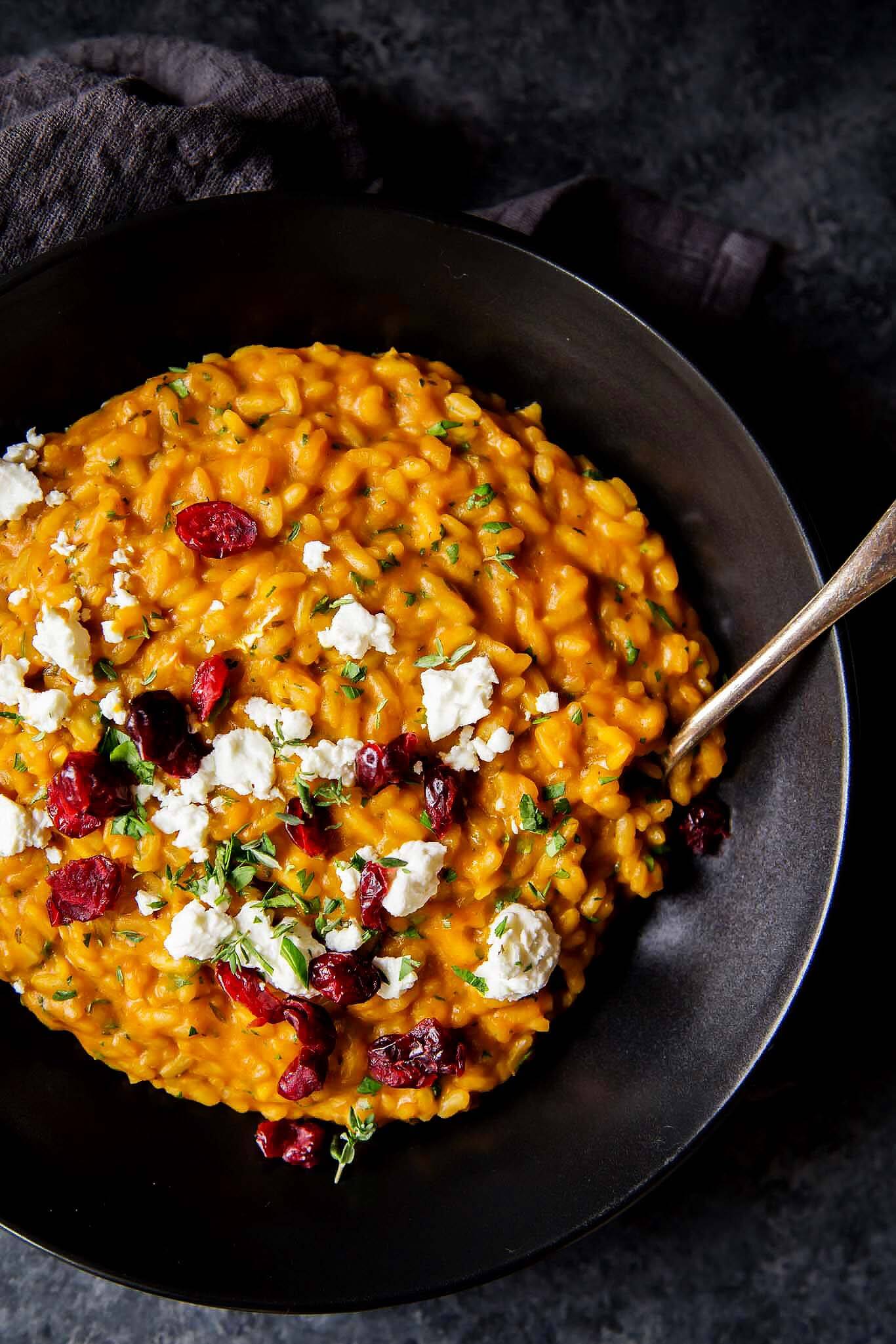 Overhead shot of pumpkin risotto in bowl with goat cheese & cranberries