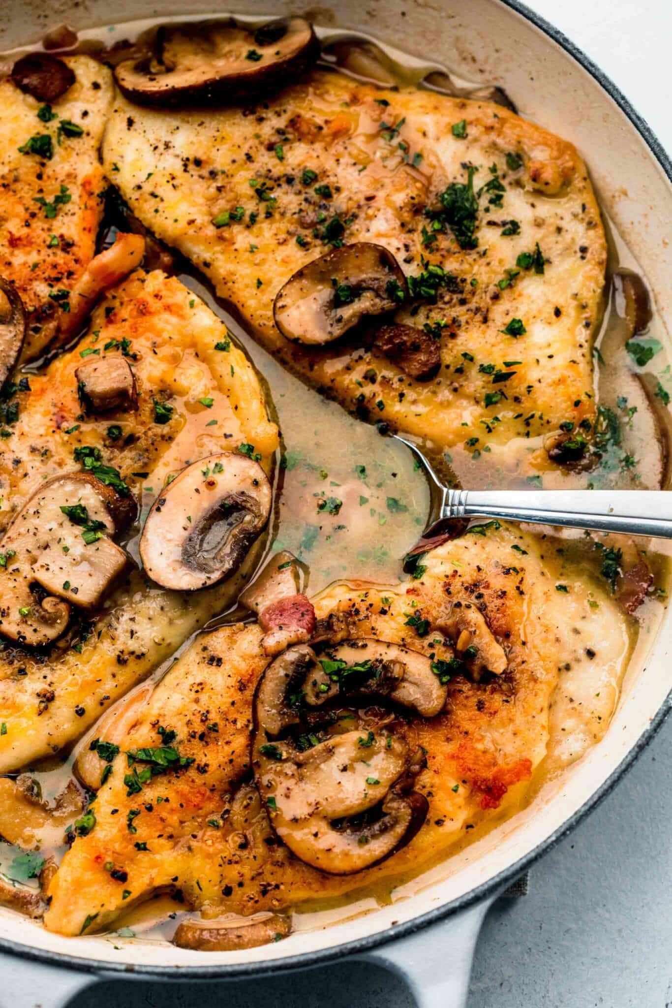 Chicken marsala in large skillet with spoon in sauce.