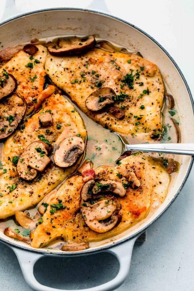Chicken marsala in large skillet with spoon in sauce.