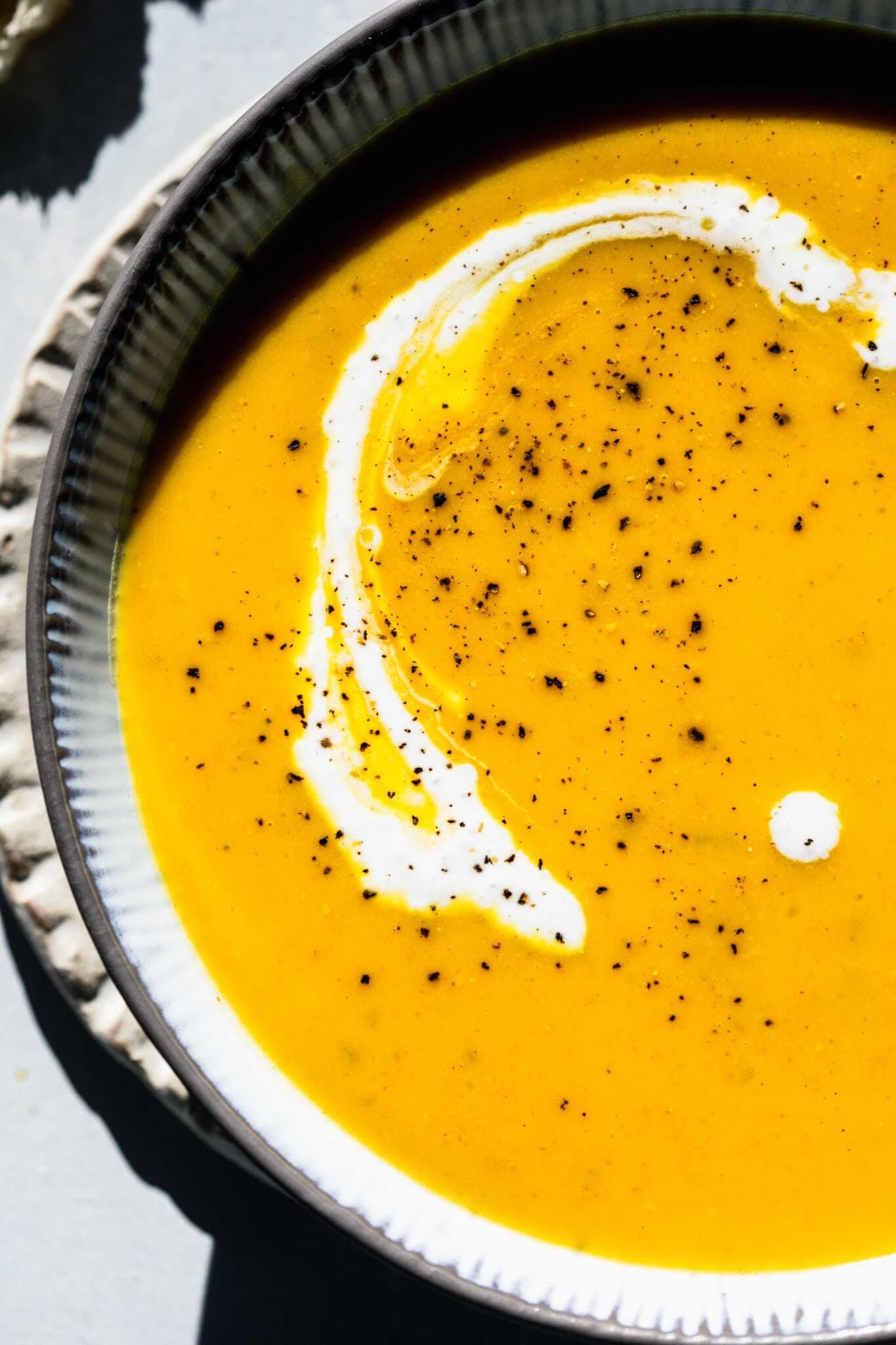 Overhead close up of bowl of butternut squash soup with dollop of sour cream.