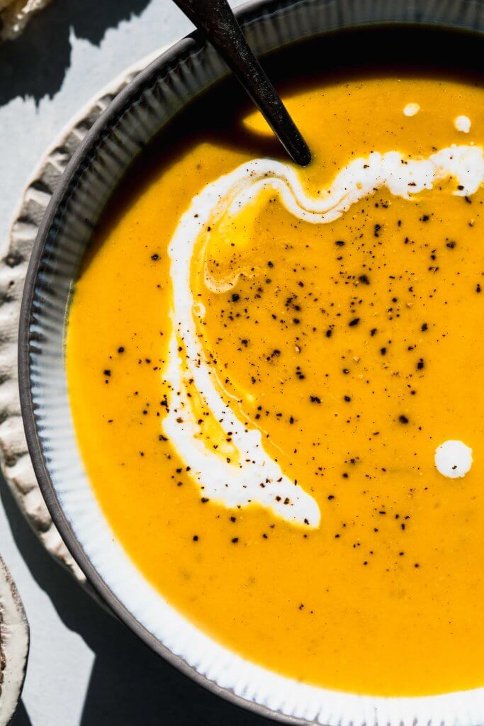 Overhead close up of bowl of butternut squash soup with dollop of sour cream.
