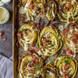 Roasted Cabbage Steaks topped with Bacon & Garlicky Creme Fraiche on a cookie sheet.