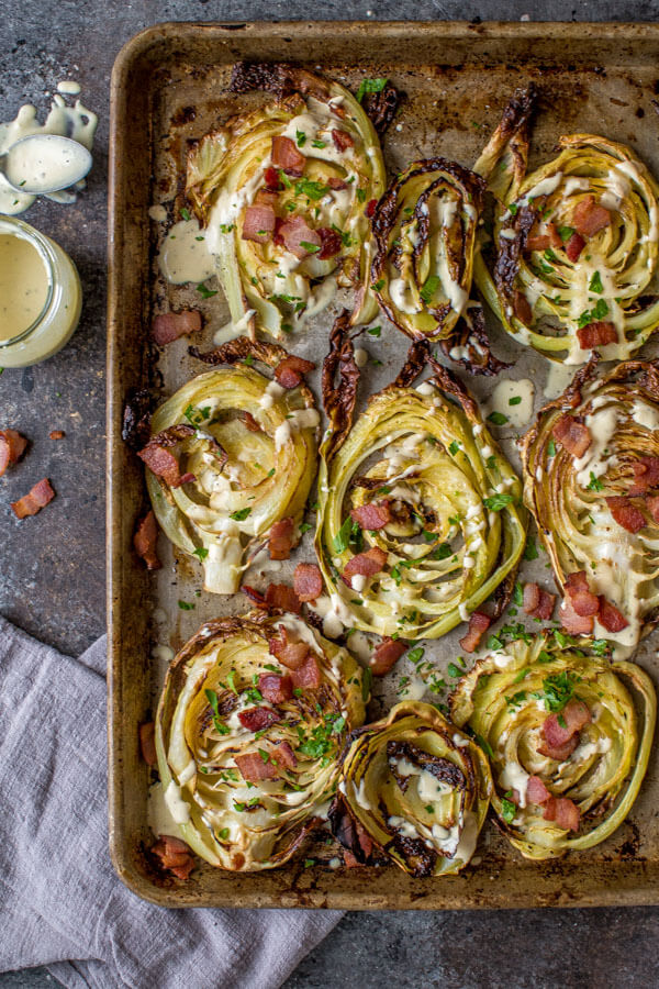 Roasted Cabbage Steaks topped with Bacon & Garlicky Creme Fraiche on a cookie sheet.