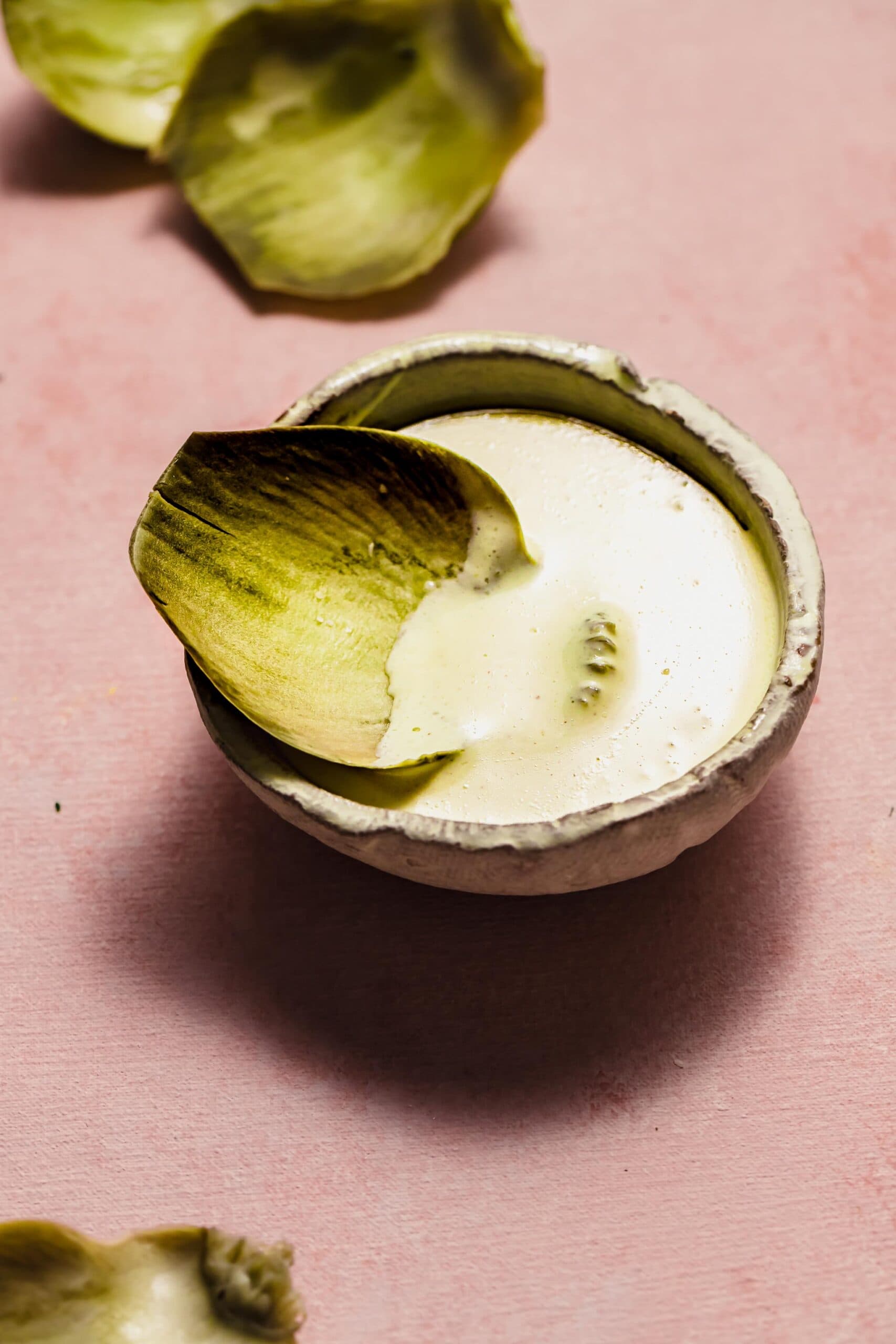 Artichoke leaf dipped into artichoke dipping sauce.