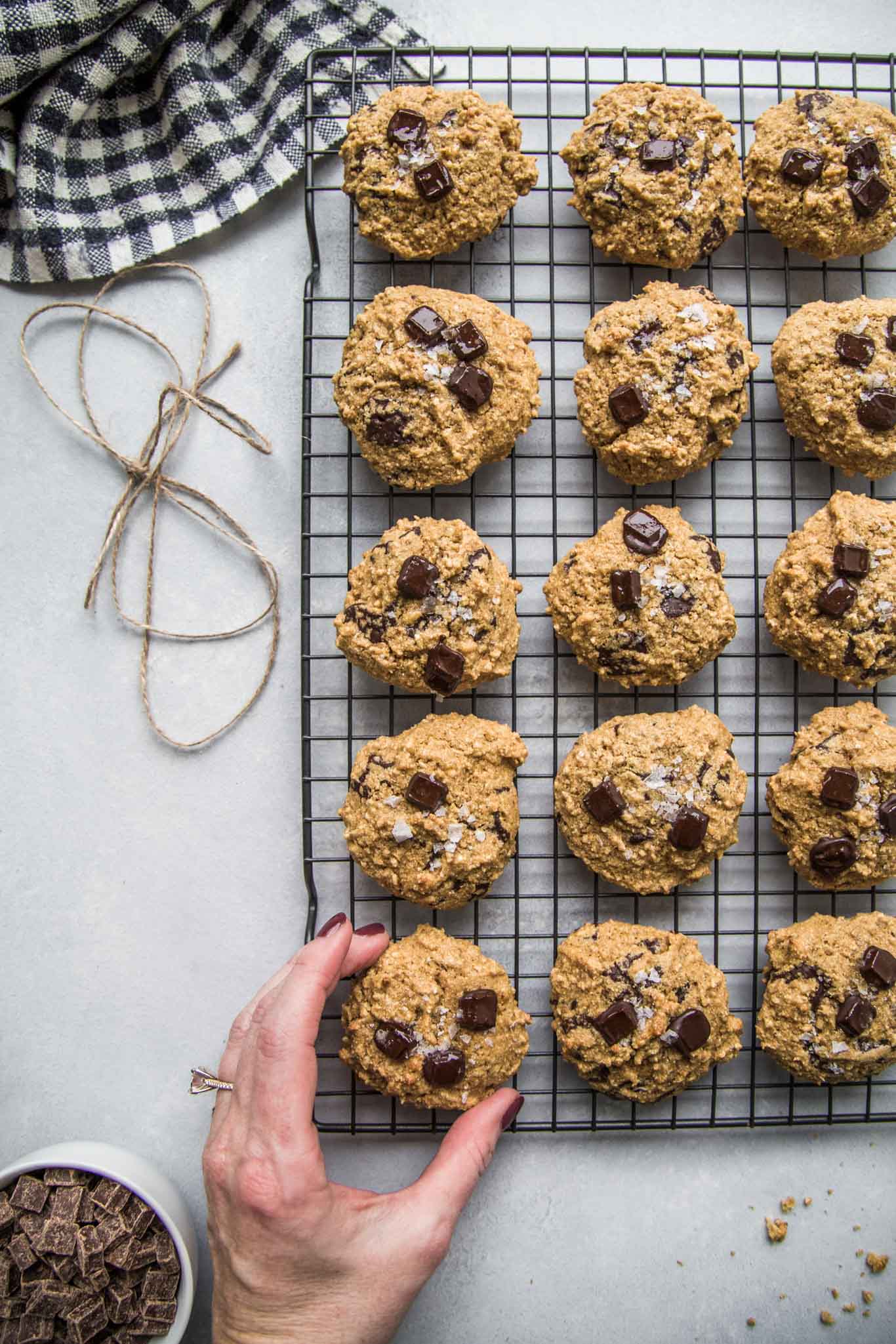 Hand reaching for quinoa breakfast cookies topped with dark chocolate and sea salt