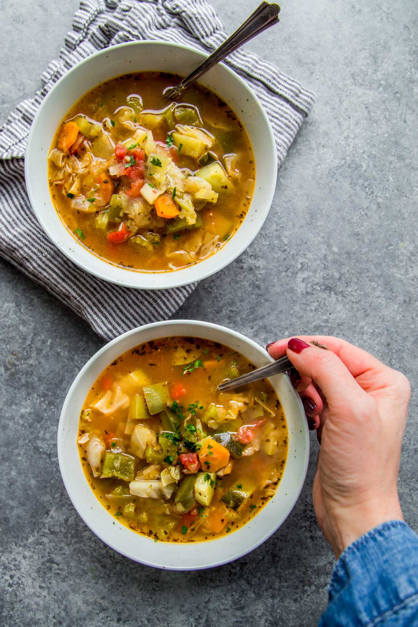 Two bowls of instant pot weight loss soup with hand eating. 