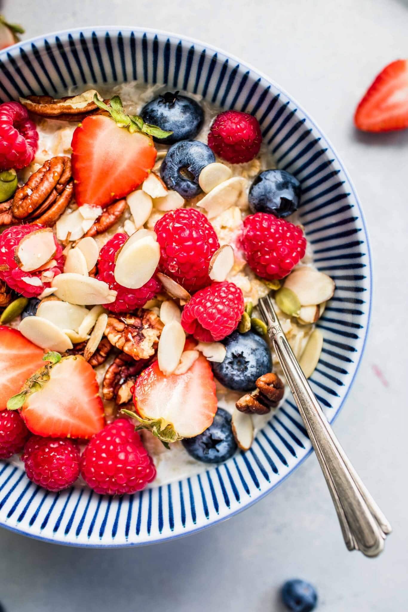 Overhead close up of bowl of oatmeal topped with berries and almonds.