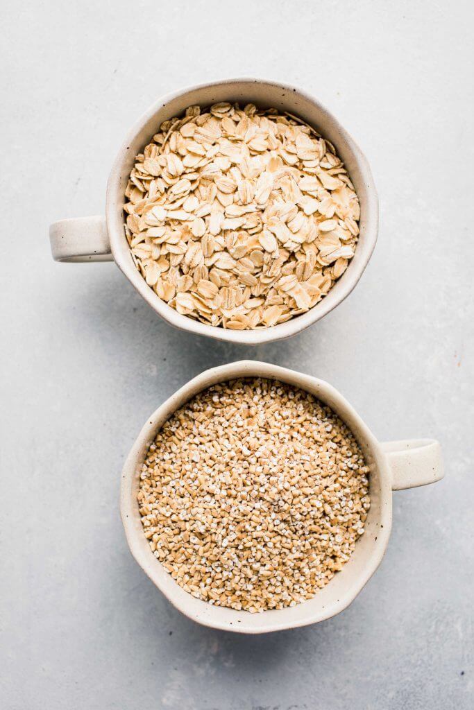 Two bowls of oatmeal, one with steel cut oats and the other with regular oats. 