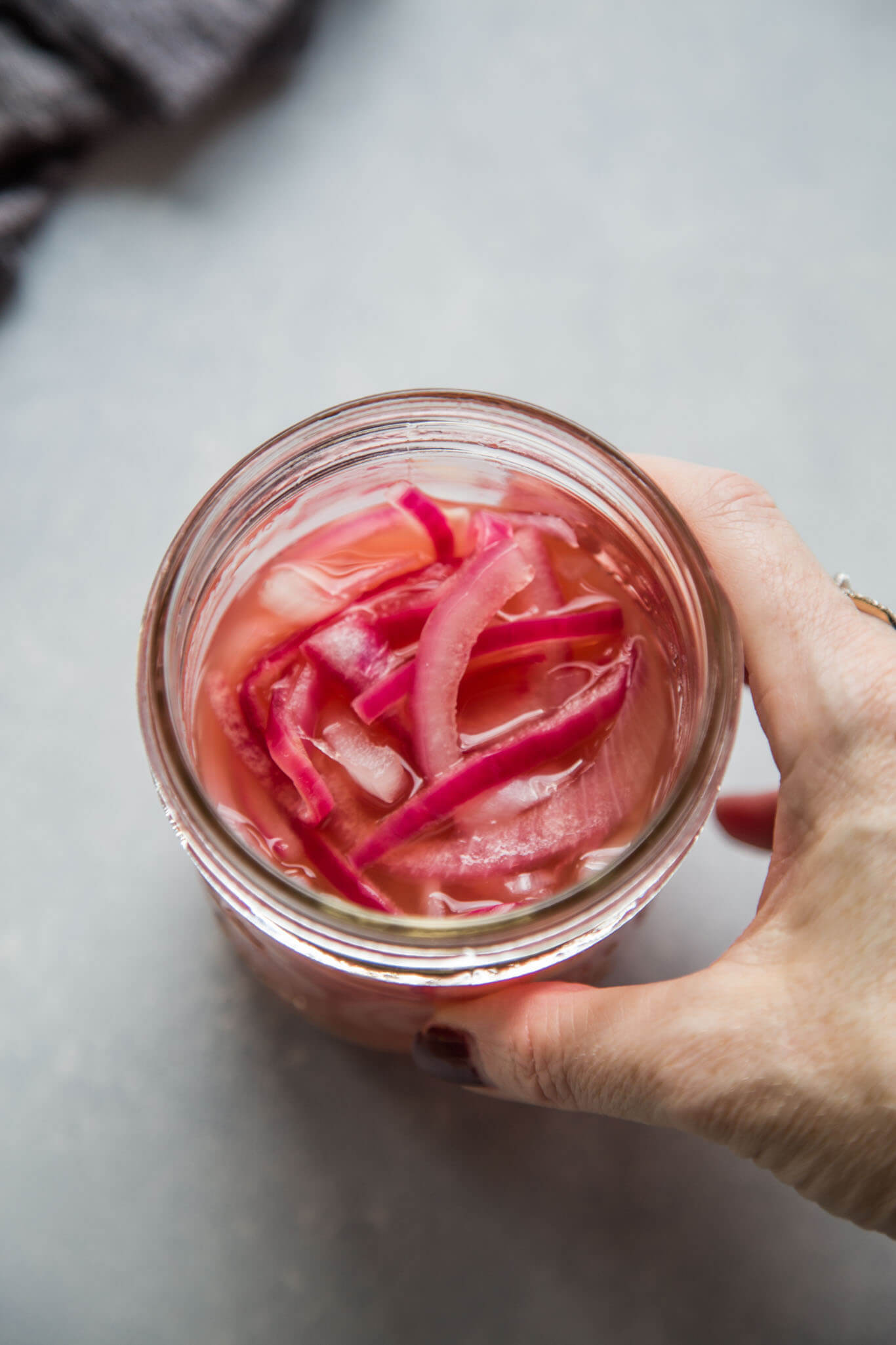 Hand reaching for jar of quick pickled onions.