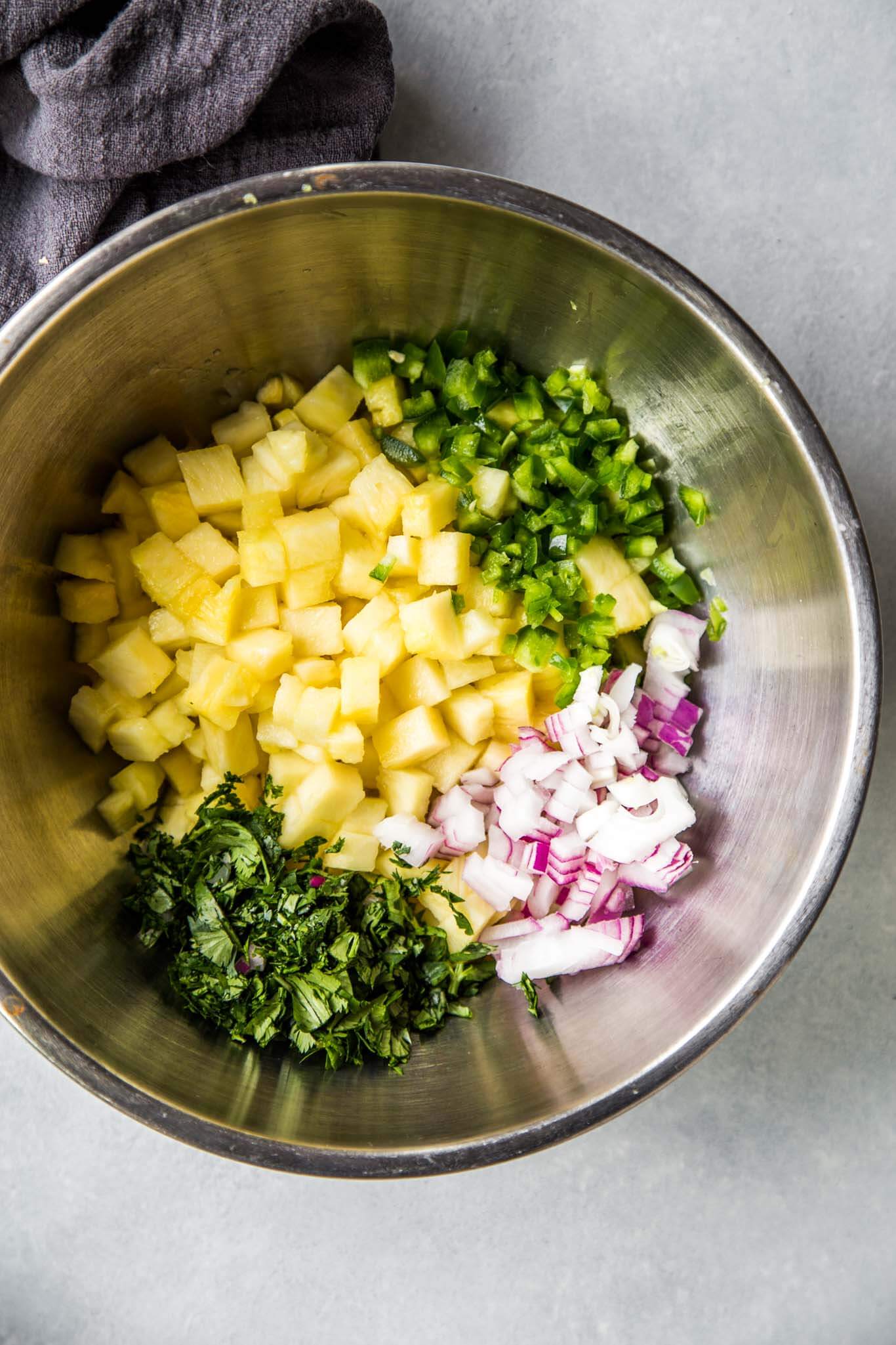 Bowl of ingredients for pineapple salsa ready to be mixed together.