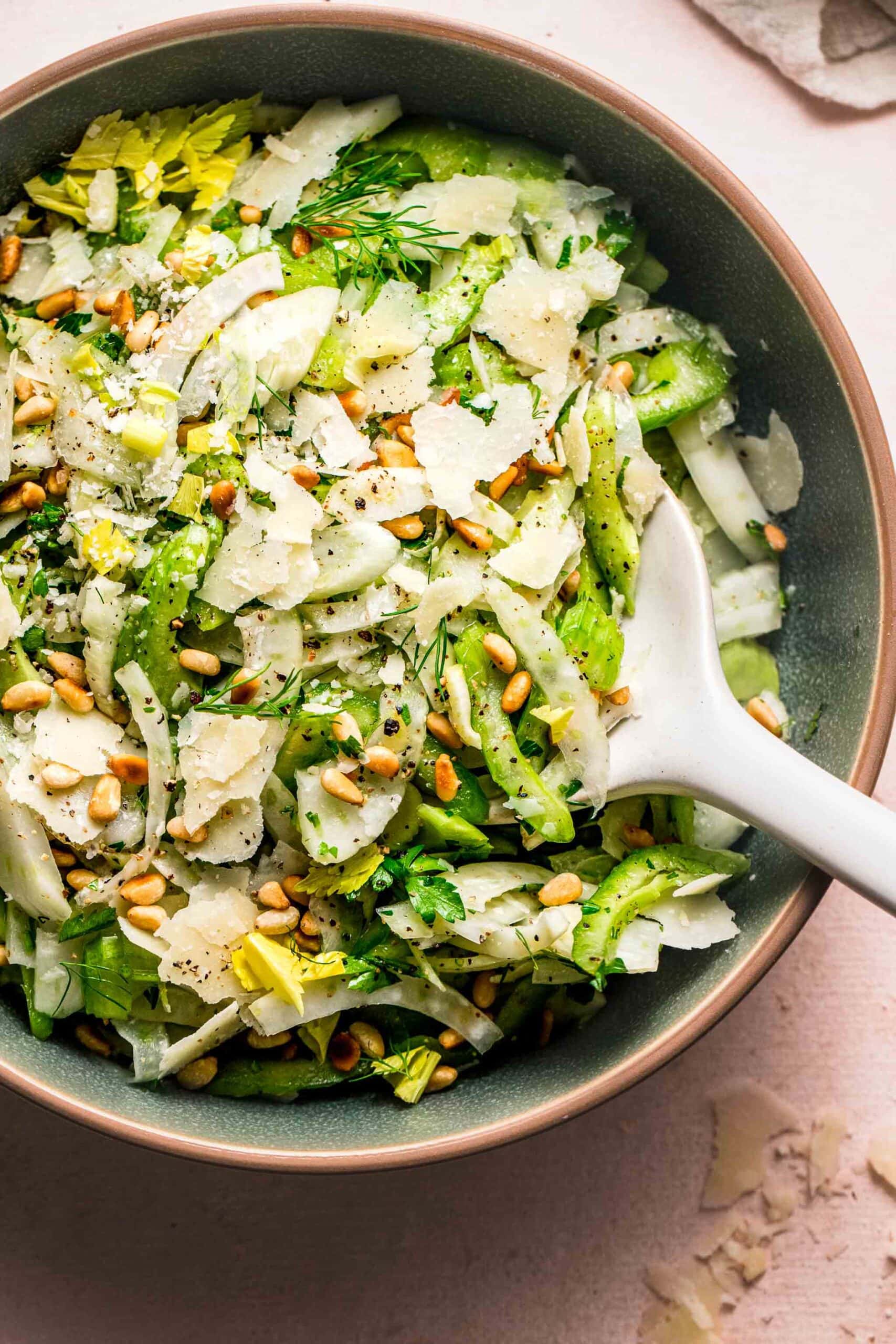 Shaved fennel salad in bowl with serving spoon.