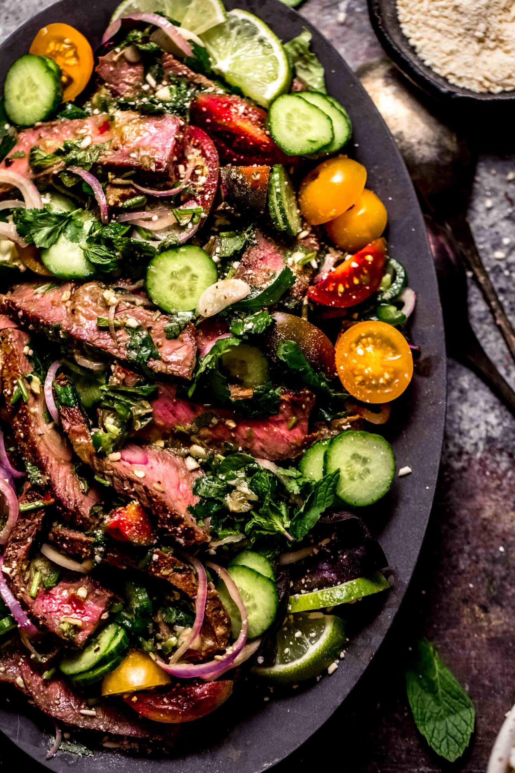 Thai beef salad arranged on a plate with toppings.