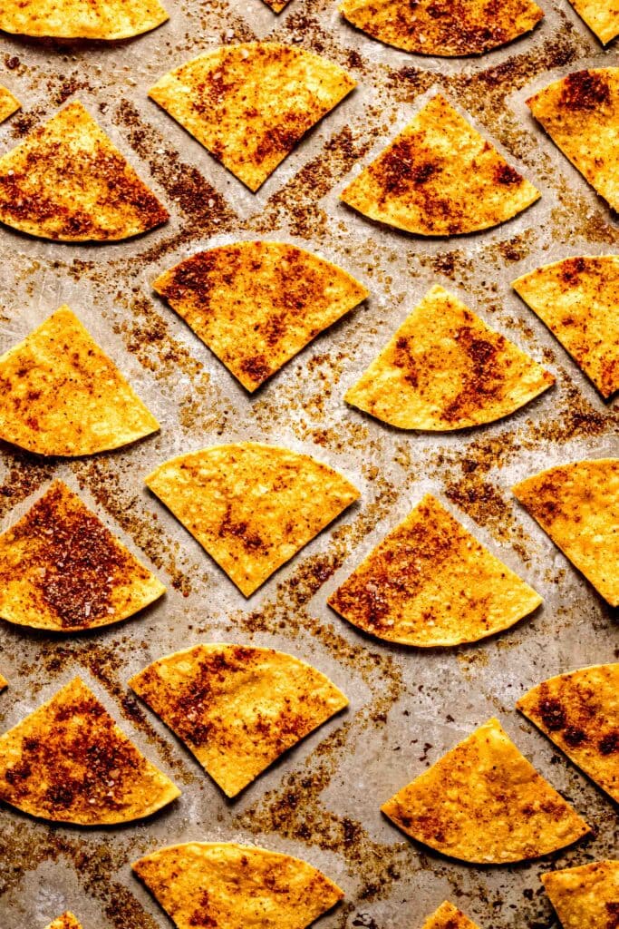 Cooked tortilla chips on baking sheet.