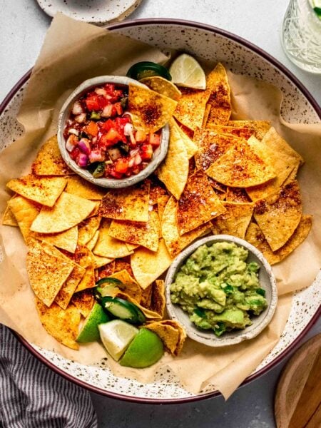 Baked tortilla chips in basket with guacamole and salsa.