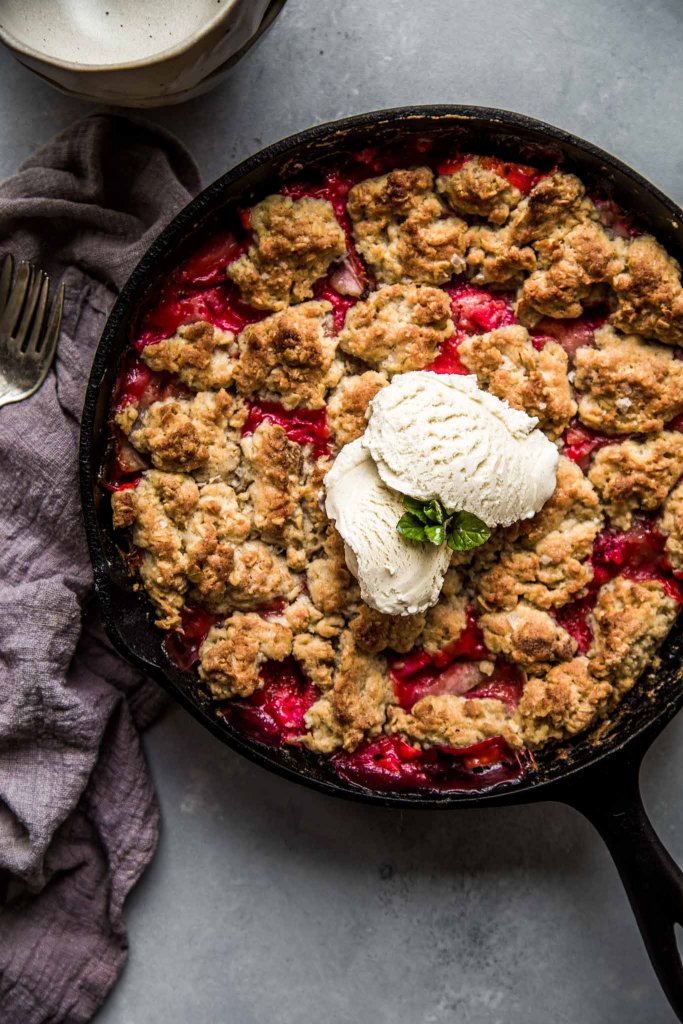 Strawberry Rhubarb Skillet Cobbler topped in cast iron skillet topped with vanilla ice cream.