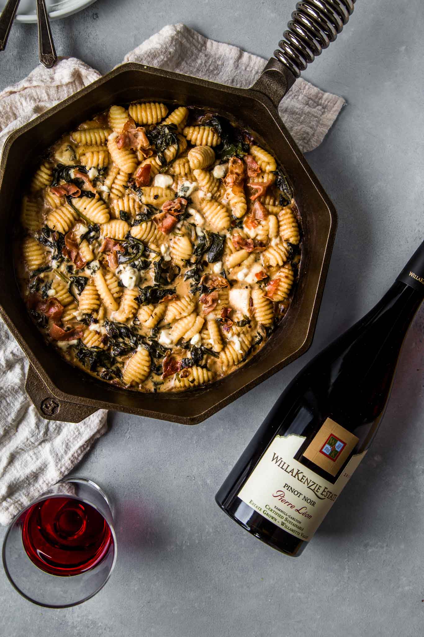 Gnocchi with Blue Cheese in skillet next to bottle of pinot noir. 