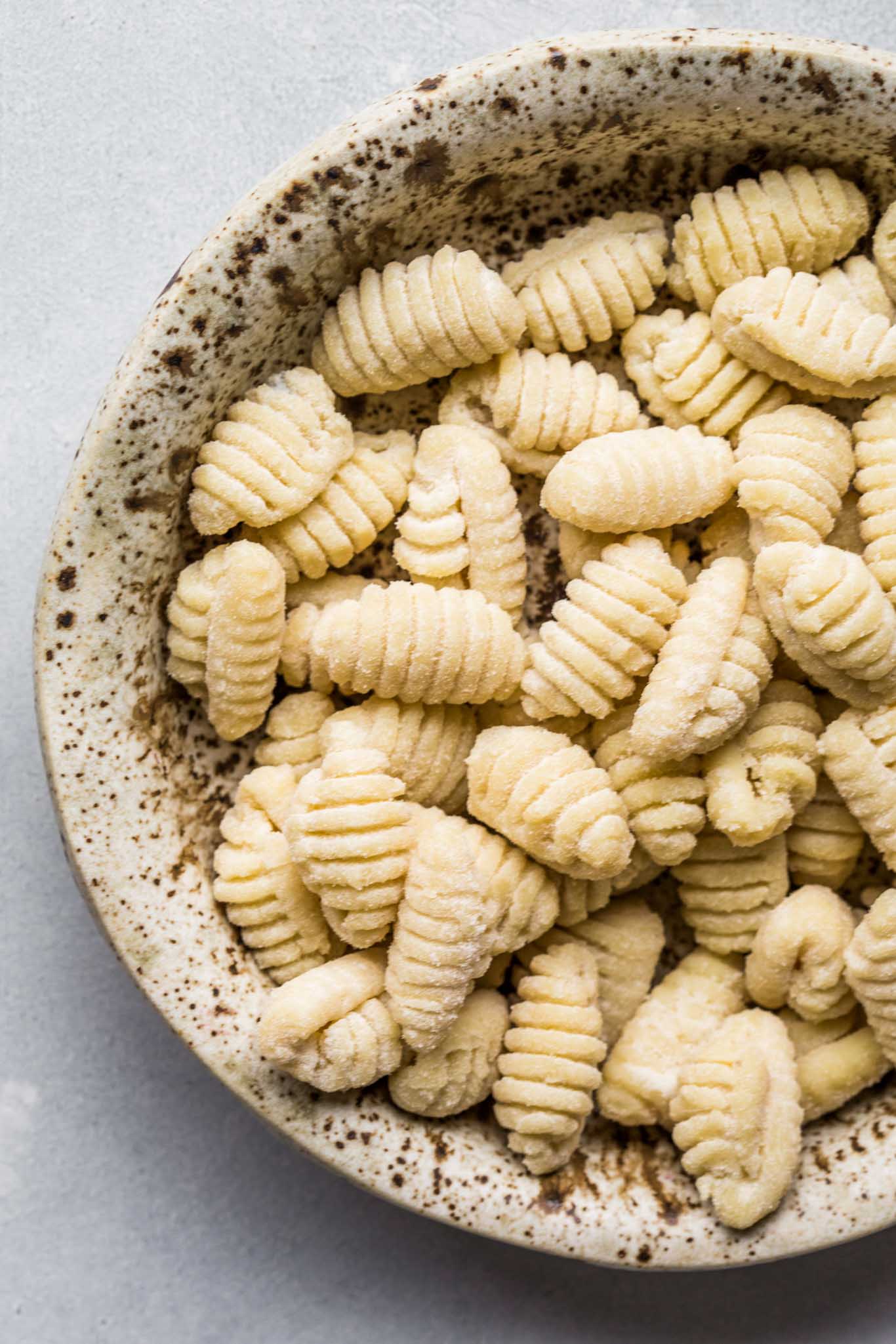 Uncooked Gnocchi in speckled bowl. 