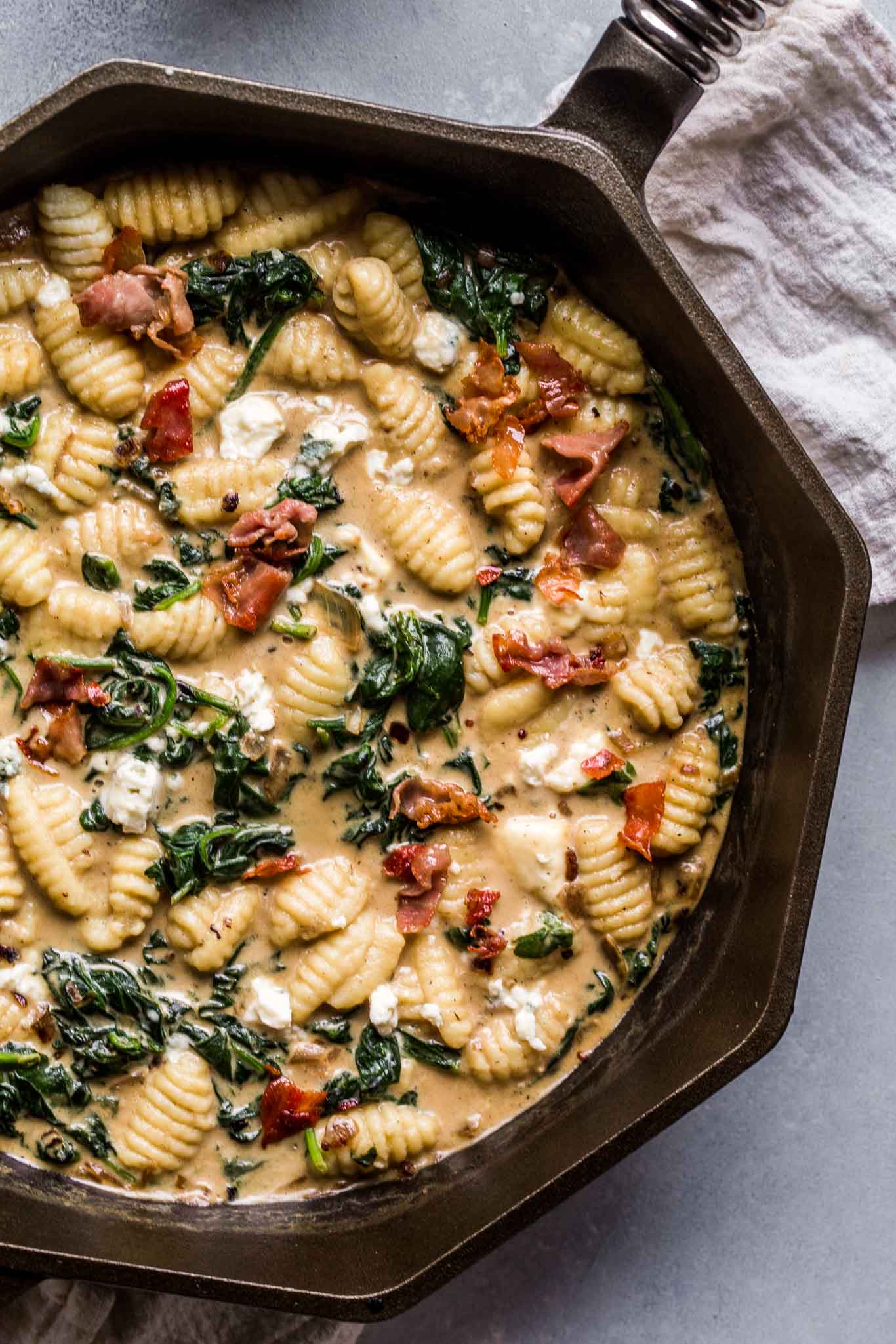 Skillet filled with gnocchi topped with blue cheese and frizzled prosciutto.